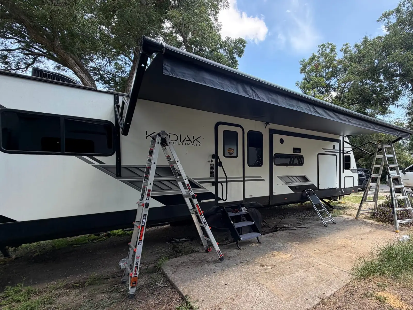 Fifth wheel with ladders set up for a new awning and slide toppers, RV awning repair and replacement