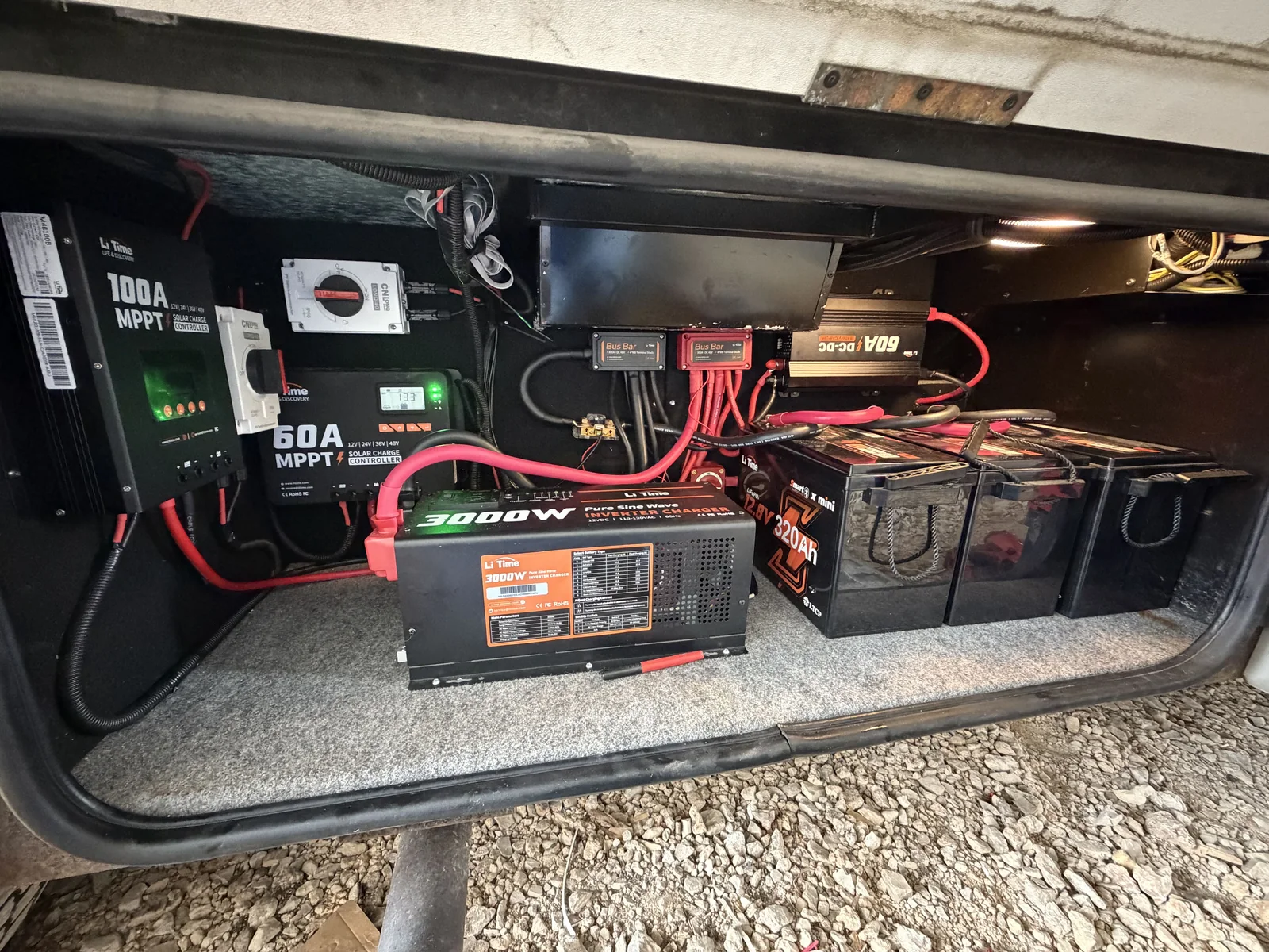 Close-up of a 3000W inverter charger, MPPT charge controllers and lithium batteries wired in an RV compartment, RV electrical repair