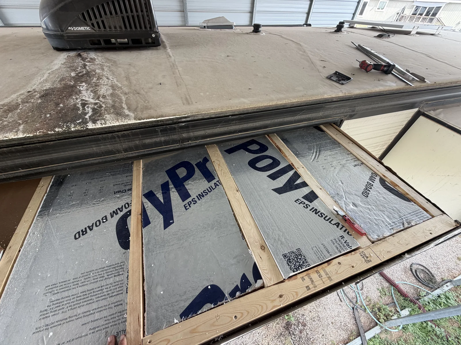 Insulation board fastened over new roof framing on a travel trailer during a roof rebuild, RV roof repair