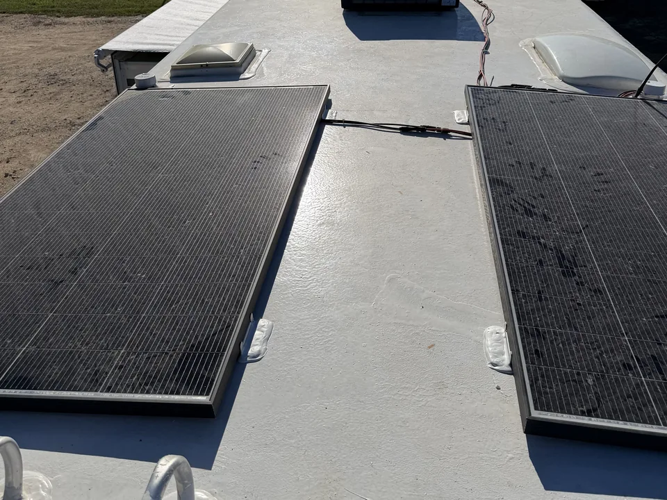 Two solar panels mounted on an RV roof with sealant over each mounting foot, RV solar installation